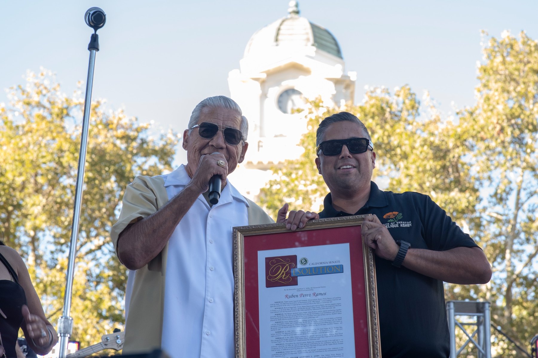 Ruben Ramos holding a California Senate Resolution onstage in Sacramento